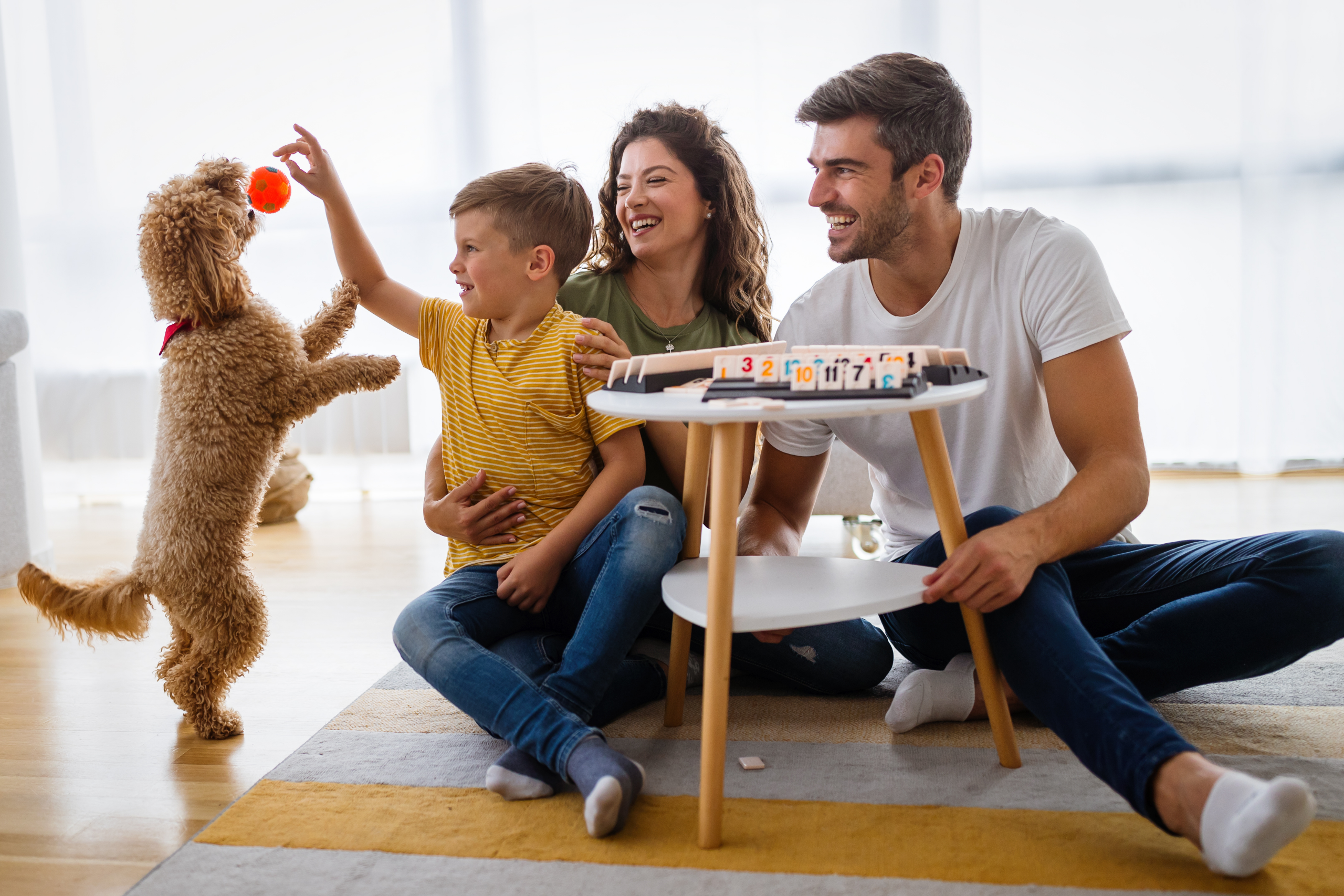 family of three sitting on floor playing with a dog